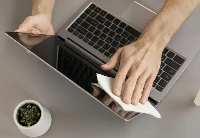 Homem fazendo a limpeza da tela do seu notebook